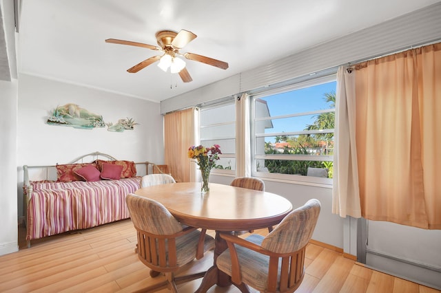 dining room featuring a ceiling fan, light wood finished floors, and baseboards