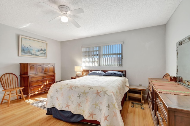 bedroom featuring light wood-style flooring, a textured ceiling, and ceiling fan