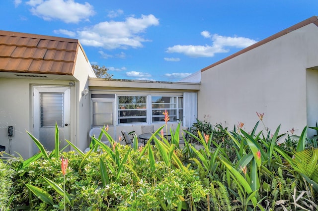 property entrance with stucco siding and a tile roof