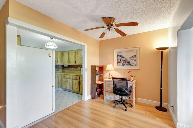 home office with ceiling fan, light wood-type flooring, a textured ceiling, and baseboards
