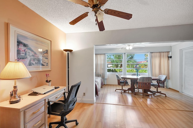 office area featuring ceiling fan, light wood-style floors, a textured ceiling, and baseboards