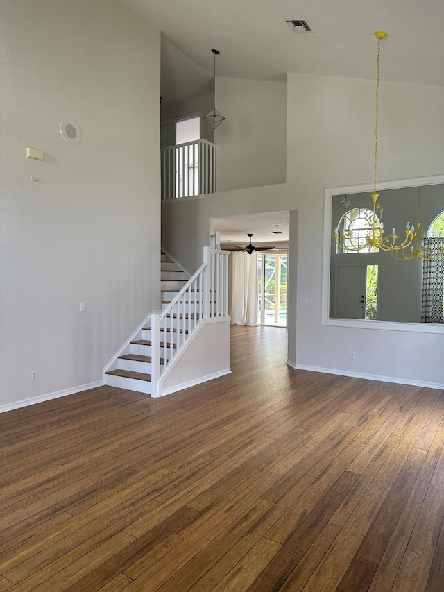 207 Pennock Trace Dr, Jupiter, FL 33458 - unfurnished living room with wood-type flooring, high vaulted ceiling, stairs, baseboards, and a chandelier