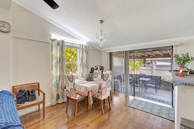 dining room featuring lofted ceiling, wood finished floors, a chandelier, crown molding, and a textured ceiling