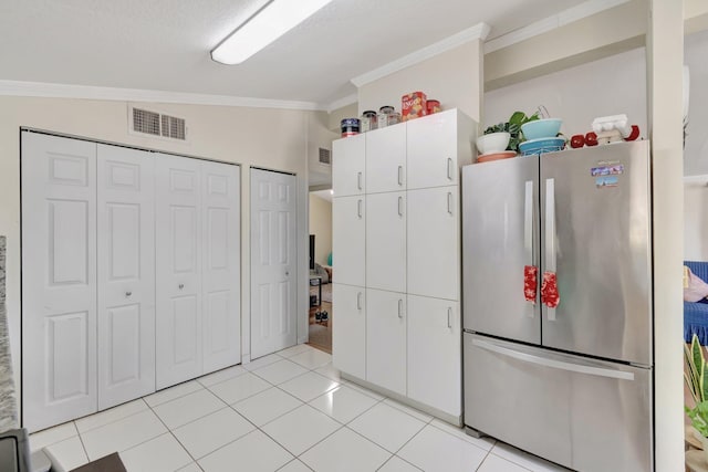 kitchen with freestanding refrigerator, crown molding, white cabinets, and light tile patterned flooring