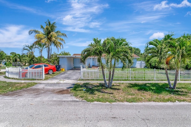view of front facade featuring asphalt driveway, an attached carport, and a fenced front yard