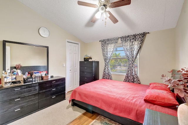 bedroom featuring vaulted ceiling, a textured ceiling, wood finished floors, and a ceiling fan