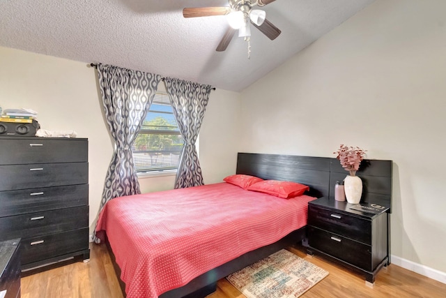 bedroom featuring light wood-style floors, vaulted ceiling, a ceiling fan, a textured ceiling, and baseboards
