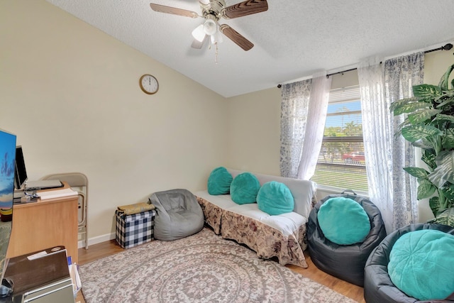 sitting room featuring a textured ceiling, a ceiling fan, and wood finished floors