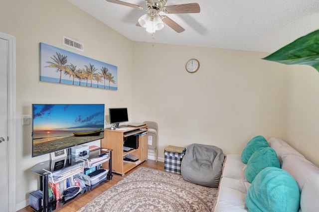 living room featuring a ceiling fan, wood finished floors, a textured ceiling, vaulted ceiling, and baseboards