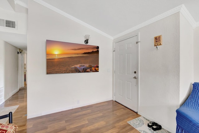 entryway featuring wood finished floors, crown molding, and baseboards