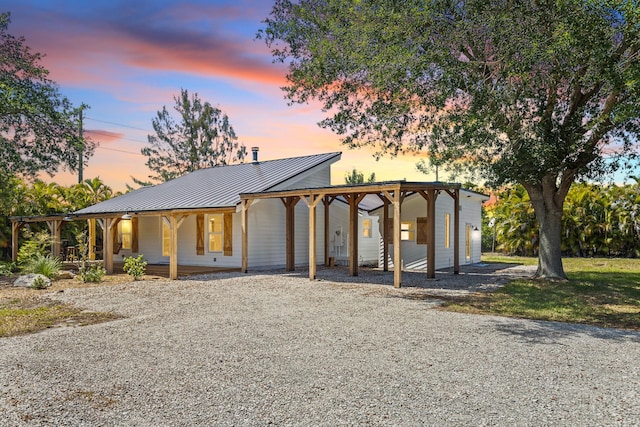 view of front of home featuring gravel driveway, covered porch, metal roof, an attached carport, and a standing seam roof