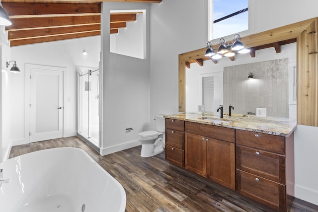 bathroom with beamed ceiling, a freestanding tub, wood finished floors, vanity, and toilet