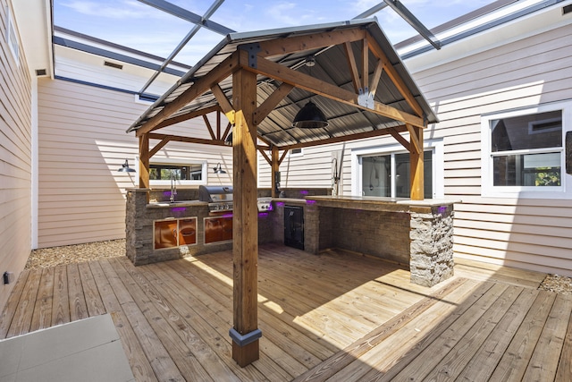 wooden terrace featuring a gazebo, an outdoor kitchen, area for grilling, and a sink