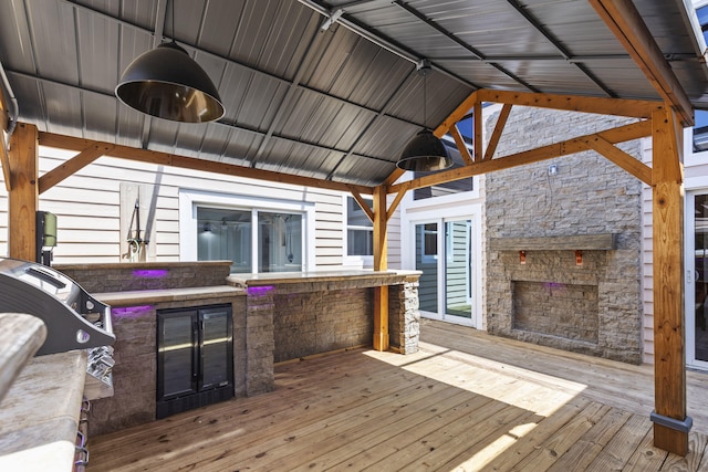 wooden terrace featuring beverage cooler, area for grilling, and a grill