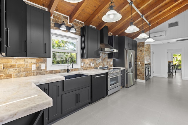 kitchen with stainless steel appliances, wood ceiling, wall chimney exhaust hood, dark cabinetry, and washing machine and dryer
