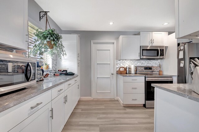 2115 SW 22nd St, Boynton Beach, FL 33426 - kitchen featuring appliances with stainless steel finishes, tasteful backsplash, white cabinets, light wood-style floors, and light stone countertops