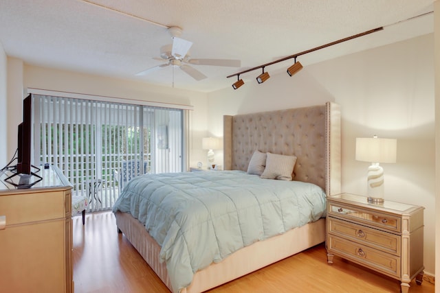 3810 Via Poinciana Unit 401, Lake Worth, FL 33467 - bedroom with access to outside, light wood-style flooring, a ceiling fan, track lighting, and a textured ceiling