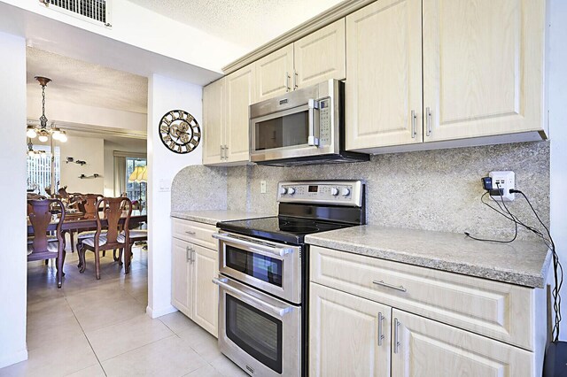 5936 Morningstar Cir Unit 201, Delray Beach, FL 33484 - kitchen with appliances with stainless steel finishes, a chandelier, light tile patterned floors, light countertops, and backsplash
