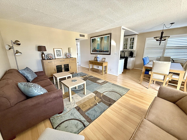 2060 Newport N, Deerfield Beach, FL 33442 - living room featuring light wood-style floors, a chandelier, a textured ceiling, and baseboards