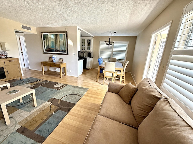 2060 Newport N, Deerfield Beach, FL 33442 - living area featuring a textured ceiling, light wood-style flooring, a chandelier, and baseboards