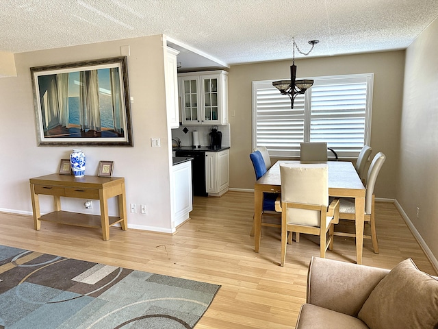 2060 Newport N, Deerfield Beach, FL 33442 - dining room featuring light wood-type flooring, a chandelier, a textured ceiling, and baseboards