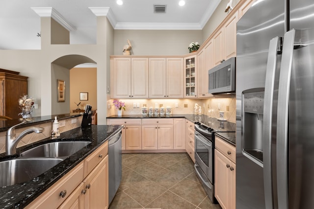 1629 SE Tradition Trce, Stuart, FL 34997 - kitchen featuring stainless steel appliances, a sink, crown molding, arched walkways, and light tile patterned floors