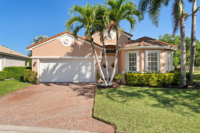 1629 SE Tradition Trce, Stuart, FL 34997 - mediterranean / spanish home with a tile roof, stucco siding, a front yard, decorative driveway, and a garage