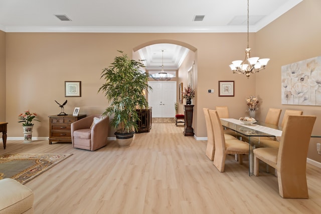 1629 SE Tradition Trce, Stuart, FL 34997 - dining space featuring arched walkways, light wood finished floors, baseboards, crown molding, and a chandelier