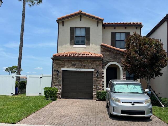 3000 King Palm Way, Riviera Beach, FL 33410 - mediterranean / spanish house with stone siding, a tiled roof, a garage, decorative driveway, and stucco siding