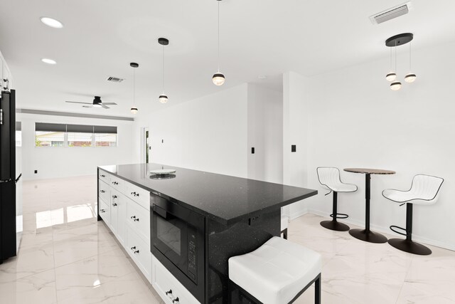 1428 N M St, Lake Worth Beach, FL 33460 - kitchen with light marble finish floors, white cabinetry, dark stone countertops, and recessed lighting