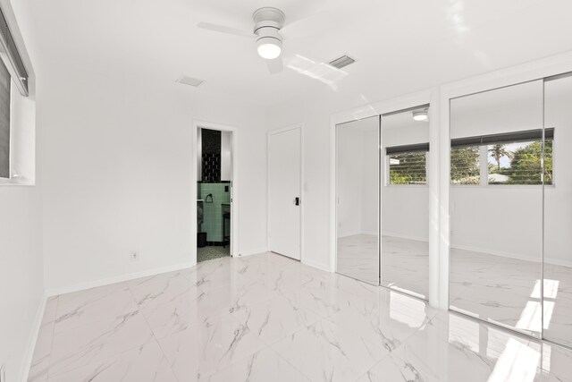1428 N M St, Lake Worth Beach, FL 33460 - unfurnished bedroom featuring two closets, marble look tile flooring, baseboards, ensuite bath, and ceiling fan