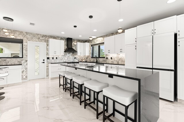 1428 N M St, Lake Worth Beach, FL 33460 - kitchen featuring wall chimney exhaust hood, light marble finish floors, freestanding refrigerator, recessed lighting, and a breakfast bar