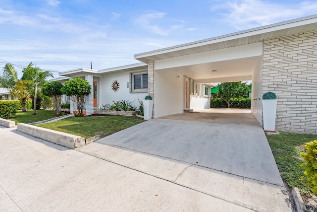 1428 N M St, Lake Worth Beach, FL 33460 - view of front facade featuring driveway, a front yard, an attached carport, and stucco siding