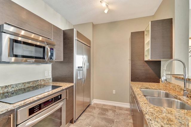 550 Okeechobee Blvd Unit 821, West Palm Beach, FL 33401 - kitchen with appliances with stainless steel finishes, a sink, baseboards, modern cabinets, and light stone countertops