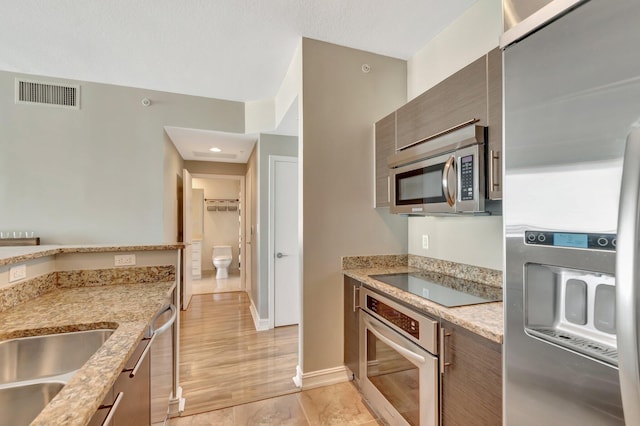 550 Okeechobee Blvd Unit 821, West Palm Beach, FL 33401 - kitchen featuring appliances with stainless steel finishes, light stone countertops, a sink, baseboards, and modern cabinets