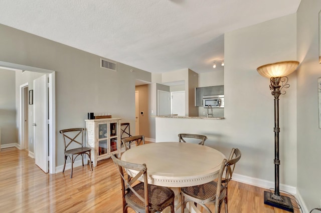 550 Okeechobee Blvd Unit 821, West Palm Beach, FL 33401 - dining space featuring light wood-style floors, baseboards, and a textured ceiling