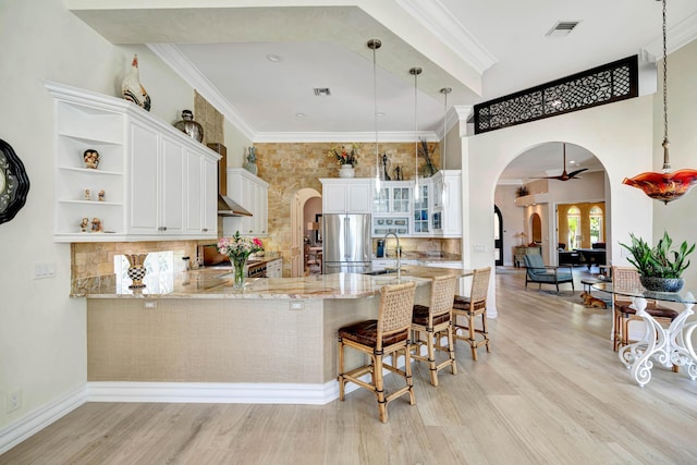 506 Corsair Dr, North Palm Beach, FL 33408 - kitchen featuring arched walkways, freestanding refrigerator, light wood-type flooring, a peninsula, and light stone counters