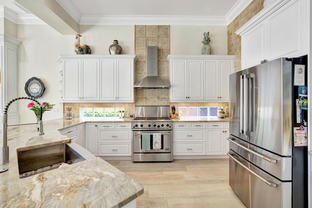 506 Corsair Dr, North Palm Beach, FL 33408 - kitchen featuring appliances with stainless steel finishes, wall chimney range hood, ornamental molding, white cabinets, and light wood-style flooring