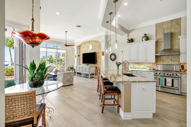 506 Corsair Dr, North Palm Beach, FL 33408 - kitchen featuring wall chimney exhaust hood, stainless steel range, a sink, open floor plan, and a kitchen breakfast bar