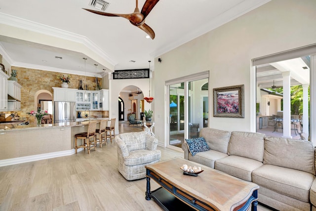 506 Corsair Dr, North Palm Beach, FL 33408 - living area featuring arched walkways, a ceiling fan, light wood-type flooring, crown molding, and a towering ceiling