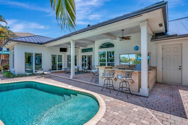 506 Corsair Dr, North Palm Beach, FL 33408 - swimming pool featuring ceiling fan, a patio, and exterior kitchen