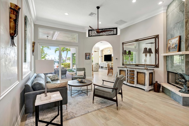 506 Corsair Dr, North Palm Beach, FL 33408 - living area with ornamental molding, arched walkways, a high end fireplace, light wood-style flooring, and recessed lighting