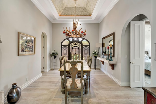 506 Corsair Dr, North Palm Beach, FL 33408 - dining room with arched walkways, a chandelier, crown molding, light wood-type flooring, and a tray ceiling
