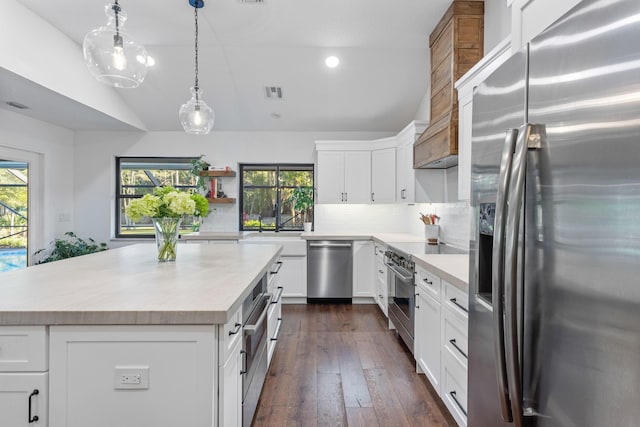 9544 Mockingbird Trl, Jupiter, FL 33478 - kitchen featuring stainless steel appliances, lofted ceiling, light countertops, tasteful backsplash, and white cabinetry