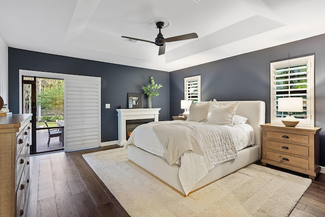 9544 Mockingbird Trl, Jupiter, FL 33478 - bedroom with a tray ceiling, multiple windows, access to exterior, and dark wood-style flooring