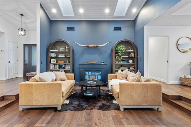 9544 Mockingbird Trl, Jupiter, FL 33478 - living area with a skylight, wood finished floors, a glass covered fireplace, built in features, and baseboards