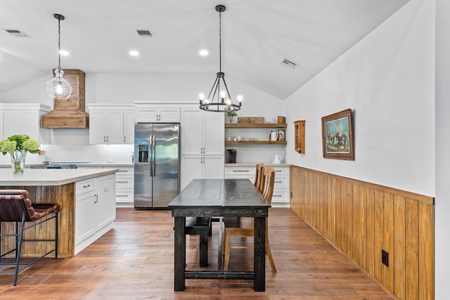 9544 Mockingbird Trl, Jupiter, FL 33478 - kitchen featuring stainless steel fridge, lofted ceiling, custom exhaust hood, wainscoting, and a chandelier