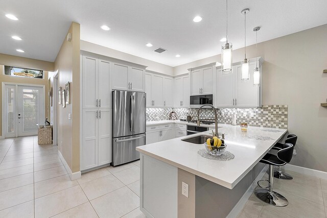 9319 Silver Shores Ln, Boynton Beach, FL 33473 - kitchen with freestanding refrigerator, a peninsula, a sink, a kitchen breakfast bar, and light countertops