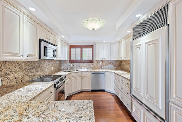 350 Beach Rd Unit 503, Tequesta, FL 33469 - kitchen featuring appliances with stainless steel finishes, a sink, a tray ceiling, light stone countertops, and decorative backsplash