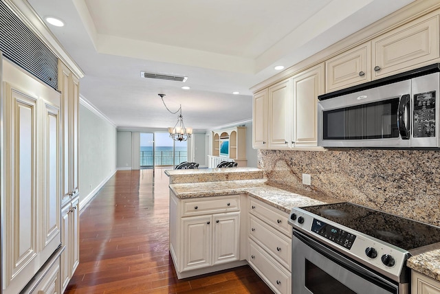 350 Beach Rd Unit 503, Tequesta, FL 33469 - kitchen with stainless steel appliances, a peninsula, cream cabinets, backsplash, and dark wood finished floors